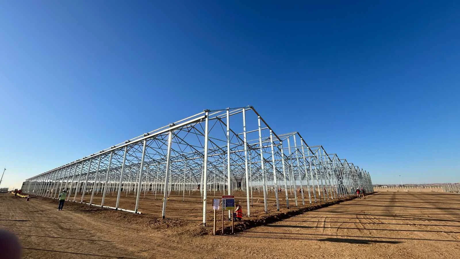 Steel greenhouse structure under construction in the desert