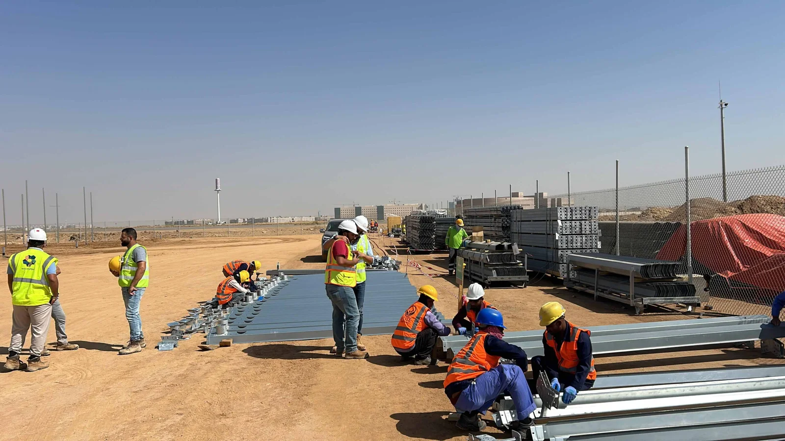 Construction crew assembling greenhouse steel framing on a Saudi project site